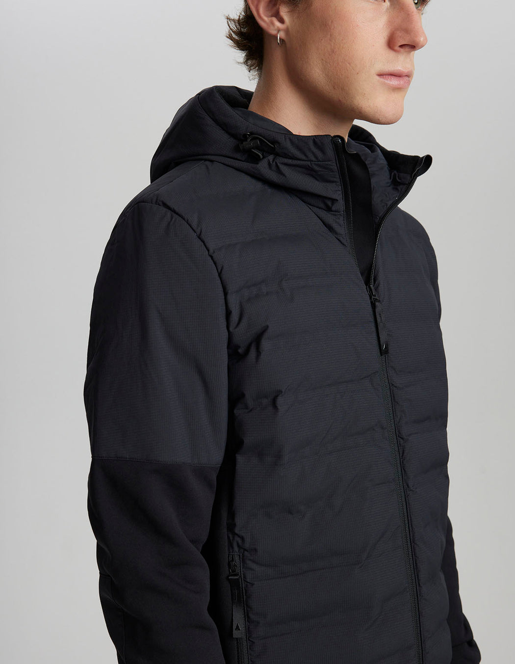 Person wearing a black puffer jacket on a plain background