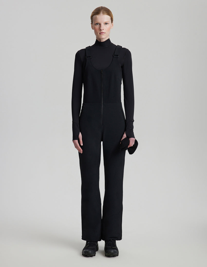 Person wearing a black jumpsuit on a light gray background
