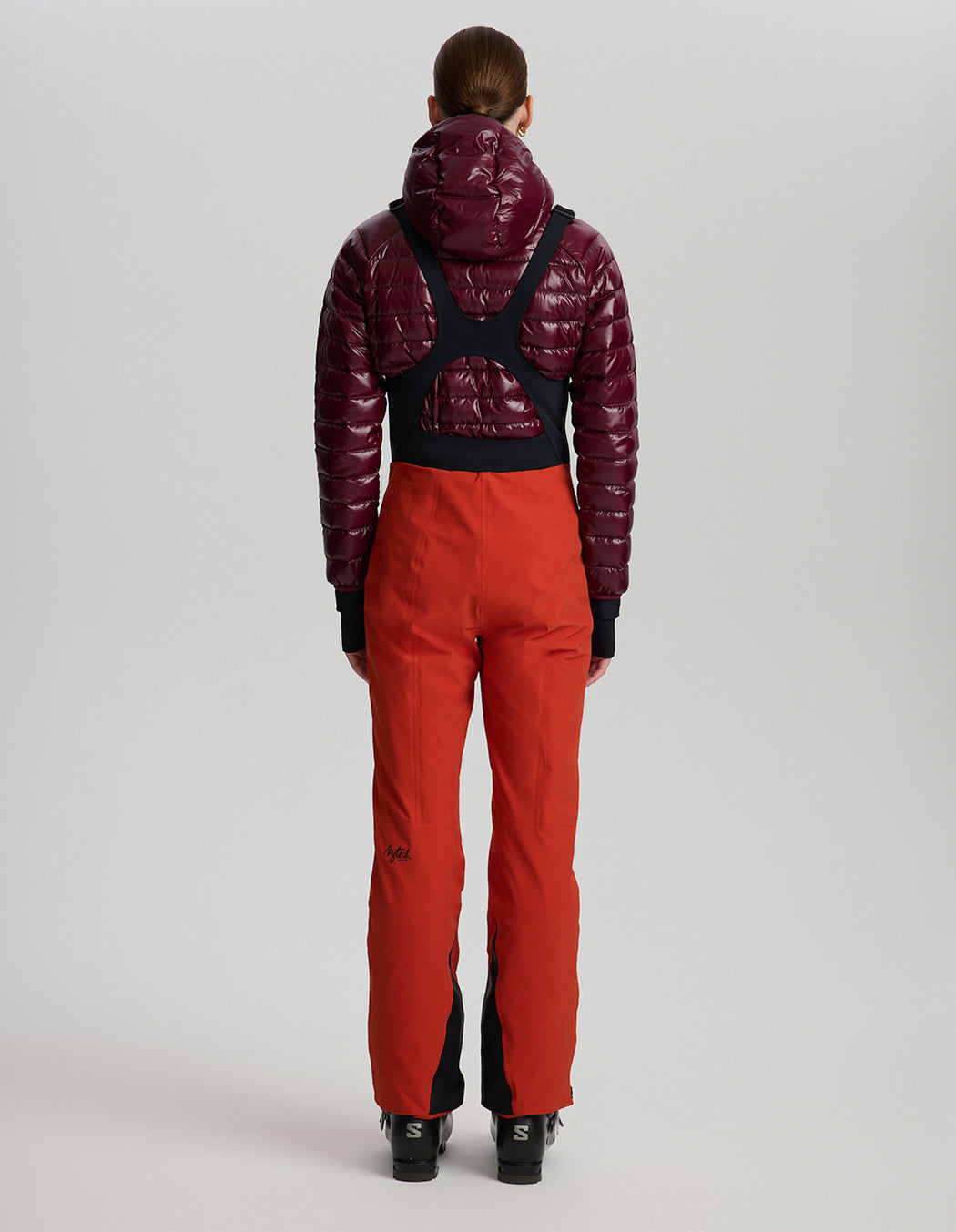 Person wearing a maroon puffer jacket and red pants on a white background