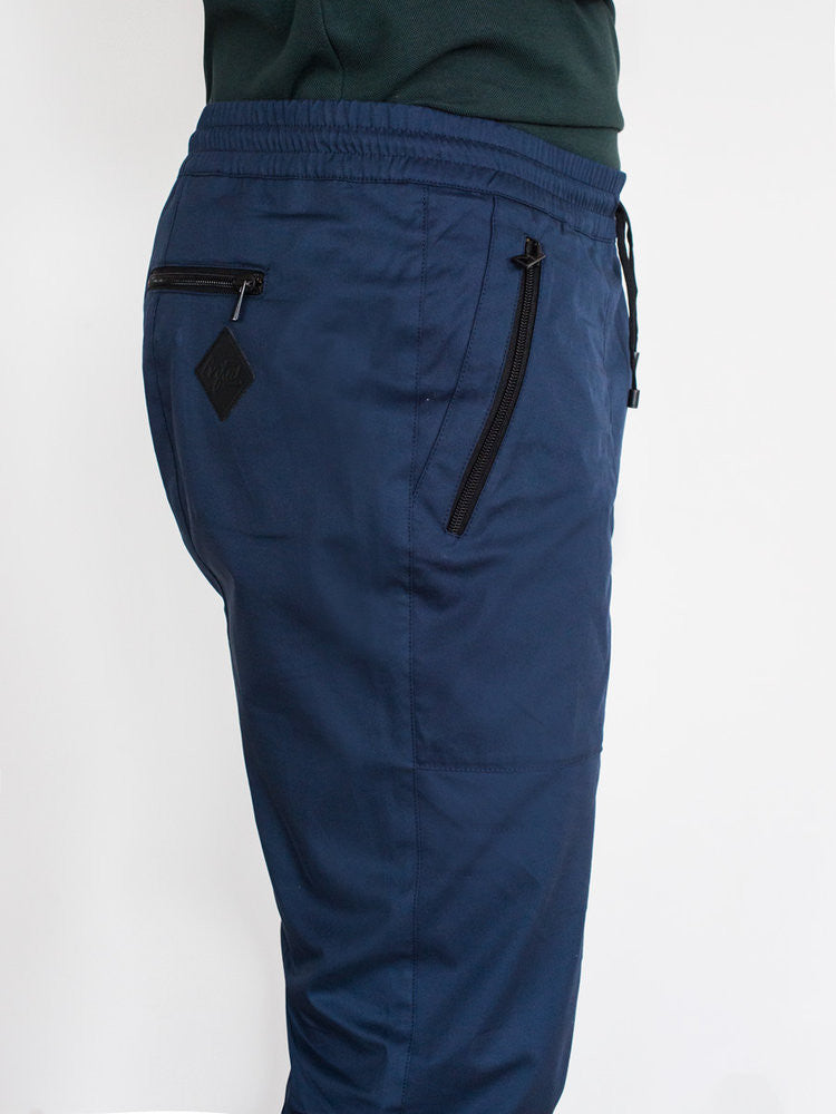 Navy cotton pants with elastic waistband and angled zippered side pocket.