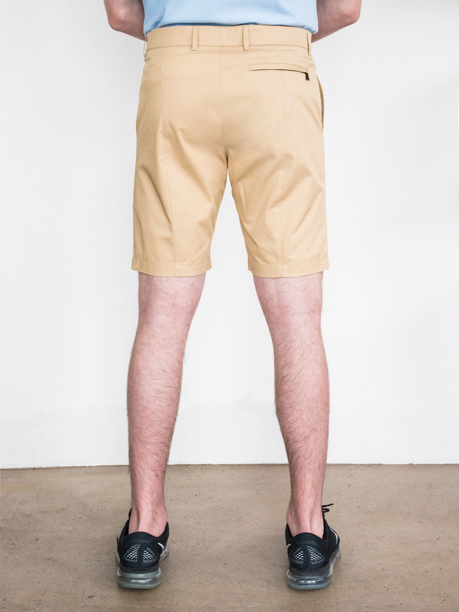 Khaki straight-fit shorts with belt loops and back welt pockets, worn with black shoes and light blue shirt.