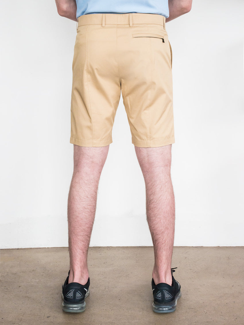 Khaki straight-fit shorts with belt loops and back welt pockets, worn with black shoes and light blue shirt.