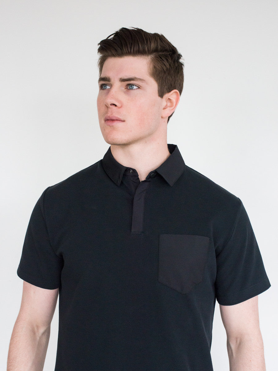 Black short-sleeve polo with button placket and chest pocket, fitted cut.