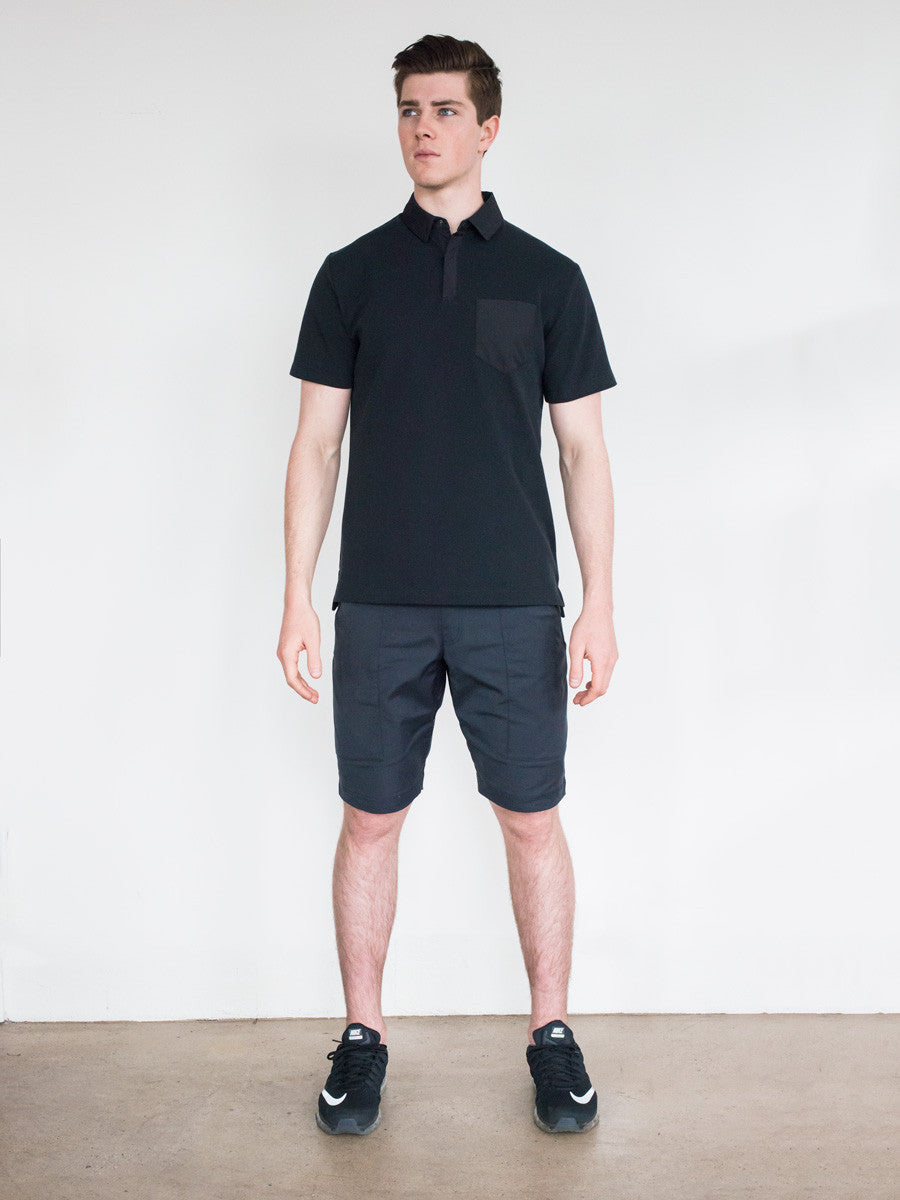 Black short-sleeve polo with buttoned collar, paired with black shorts and sneakers.