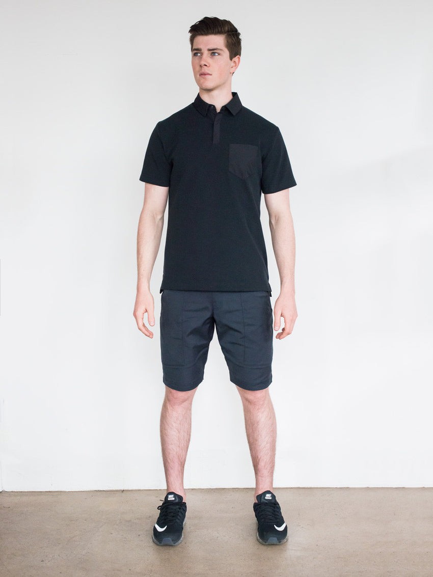 Black short-sleeve polo with buttoned collar, paired with black shorts and sneakers.
